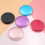 Kleiner, faltbarer, tragbarer runder Kosmetikspiegel mit Klappmechanismus, erhältlich in Schwarz, Lila, Hellblau und Rot.